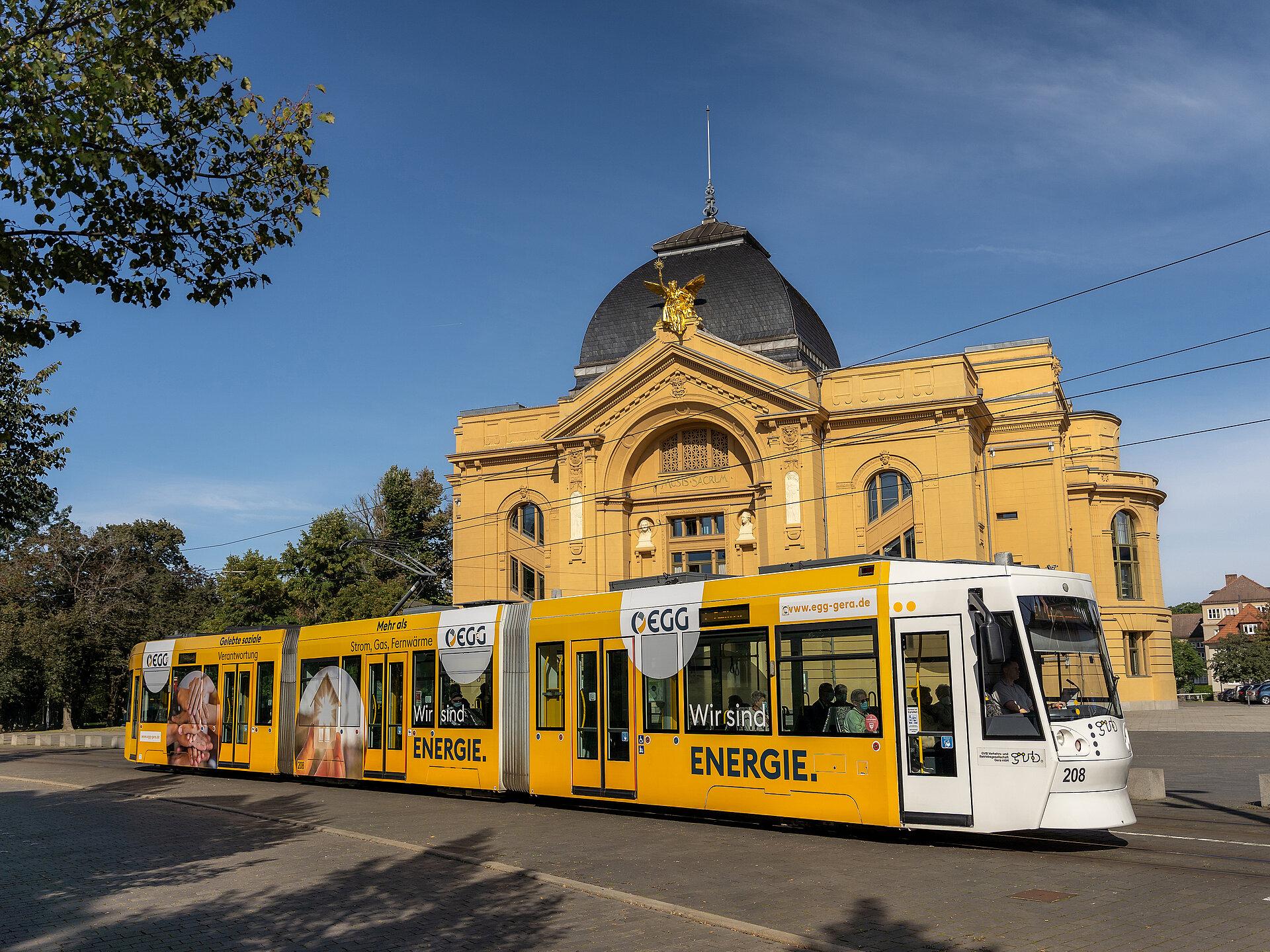 Eine Geraer Straßenbahnen im Design der EGG vor dem Geraer Theater bei Sonnenschein 
