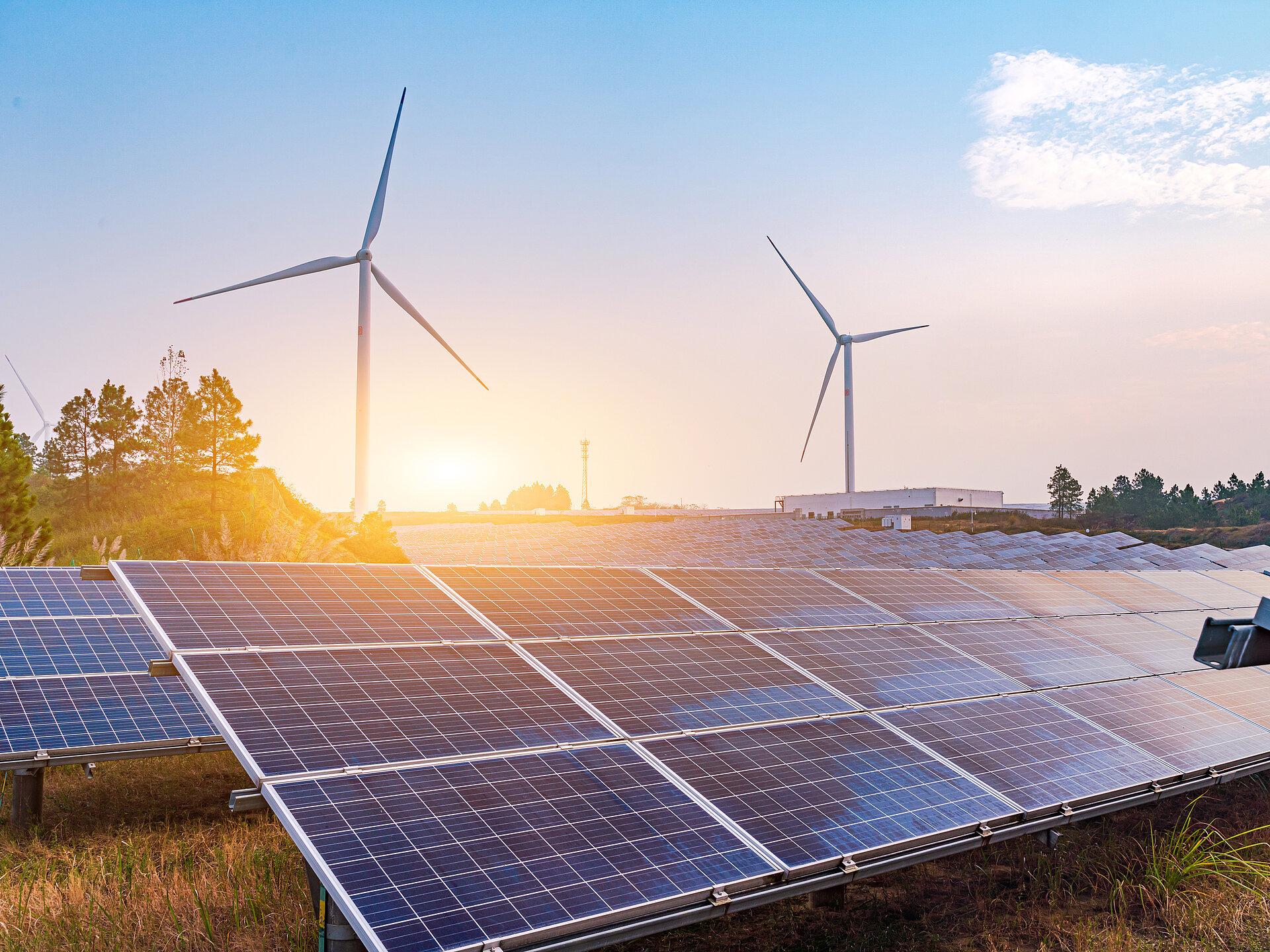Solarplatten und Windrädern die in einem Gewerbegebiet stehen bei Sonnenuntergang